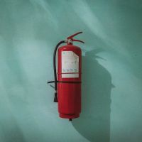 red fire extinguisher on green wall